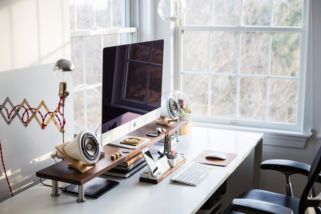 What Makes a Productive Workspace? (A Practical Guide) A clean, minimalist workspace with a white desk, ergonomic chair, monitor, keyboard, and a plant. The layout is uncluttered and designed for focus.